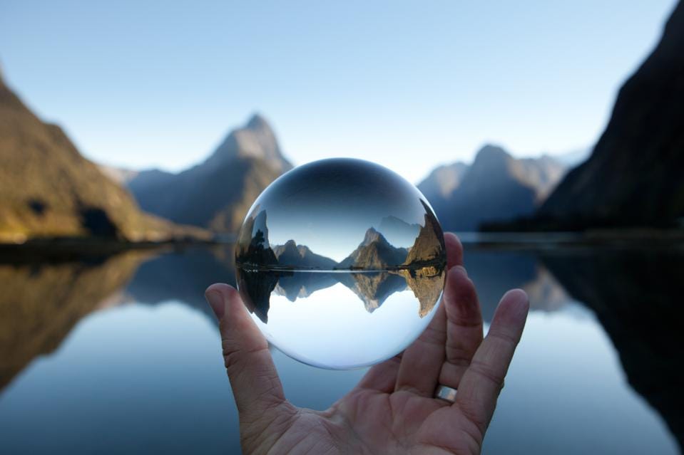 man holding crystal ball in front of landscape