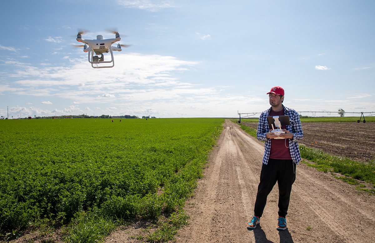 Sadegh Ranjbar, a Ph.D. student in biological systems engineering, prepares a drone for a data collection flight over an alfalfa field at Arlington Agricultural Research Station. Photo by Michael P. King