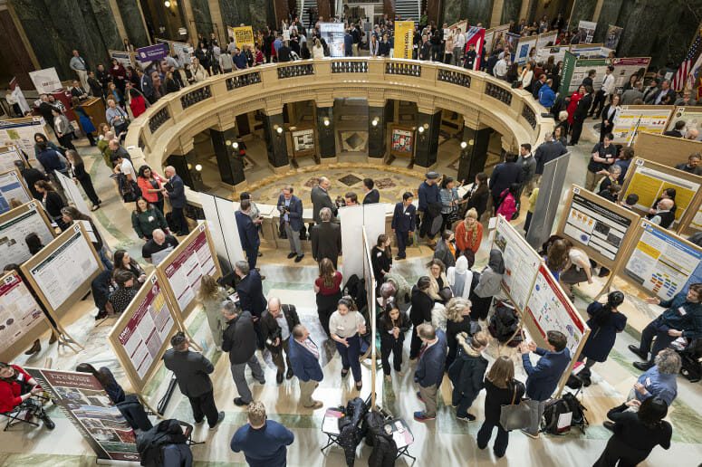 UW-Madison students, at bottom, present their research project displays as people fill the Wisconsin State Capitol during Research in the Rotunda on March 8. PHOTO BY: BRYCE RICHTER
