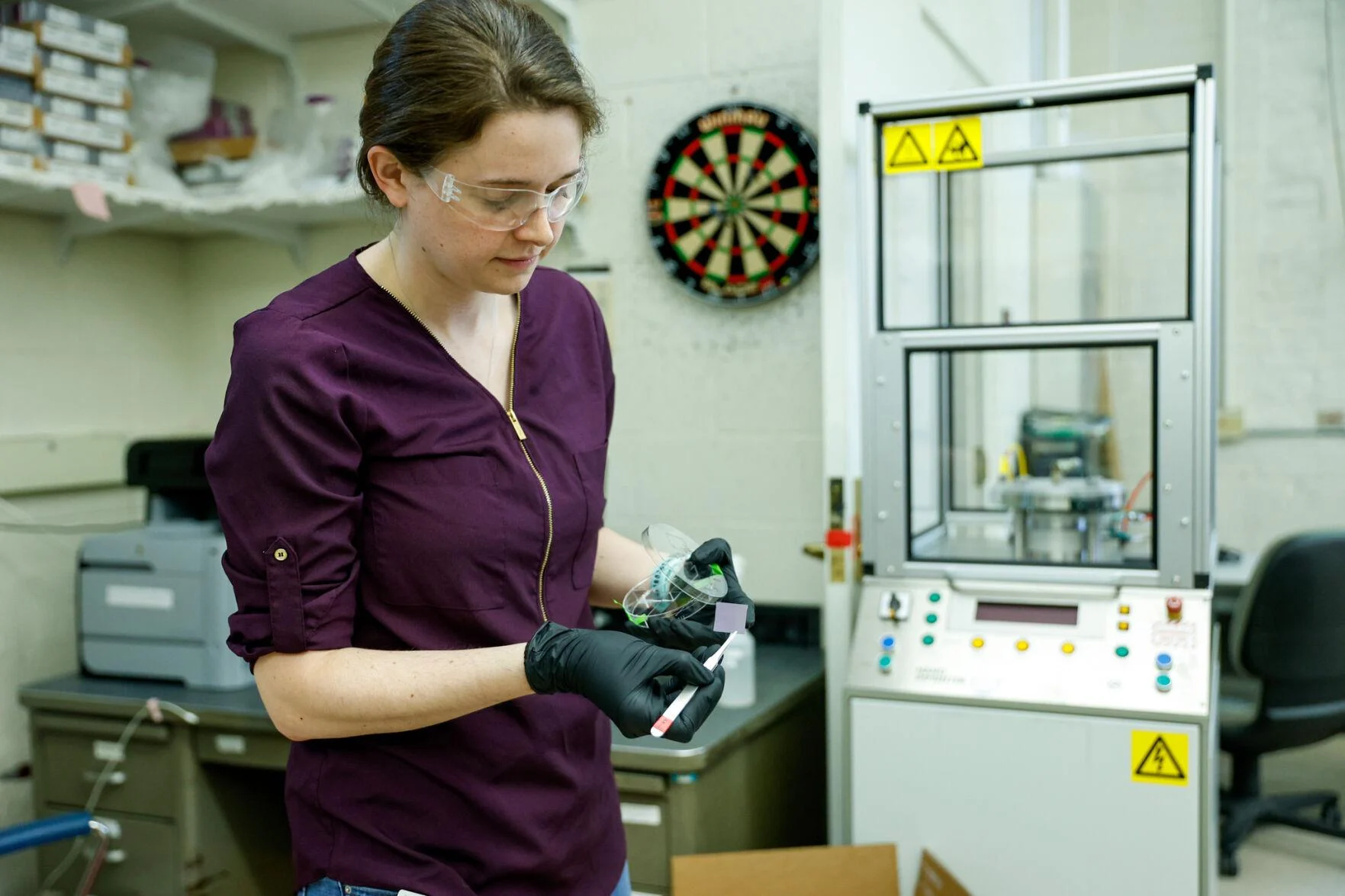 Katy Jinkins, CEO and cofounder of SixLine Semiconductor, shows a silicon piece that holds millions of carbon nanotubes. The darker purple area is where the nanotubes are concentrated. ASHLEY RODRIGUEZ